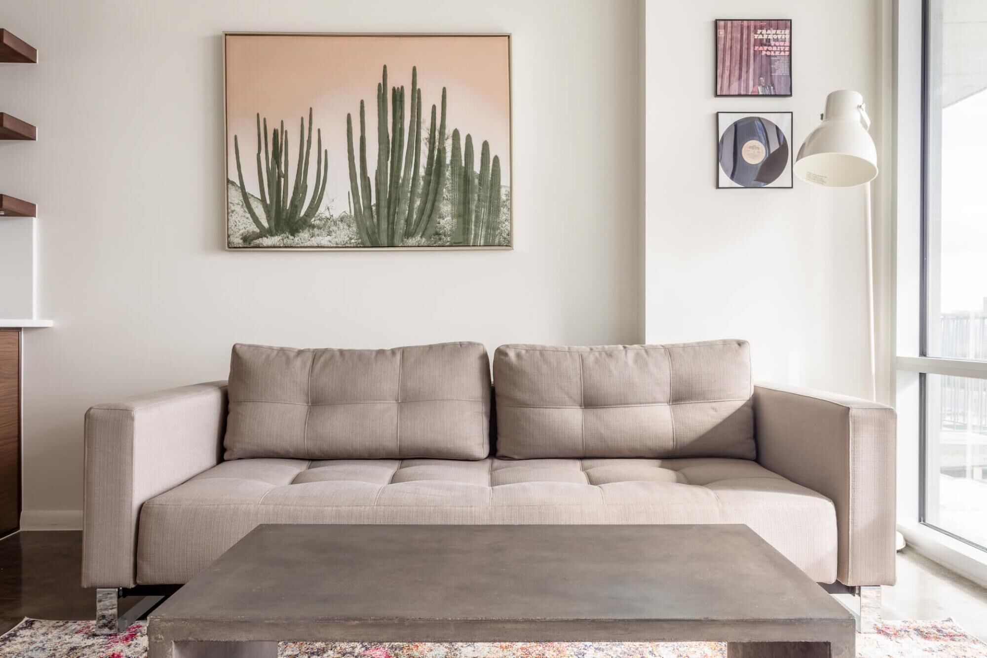 Un salon moderne avec un canapé beige, une table basse et des œuvres d’art accrochées au mur.