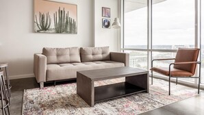 A modern living room with a sofa, a coffee table, and a chair. There is a large window with a view of the city. - Austin Sensational 1BD 1BA 2nd Street District Apartment (Austin)
