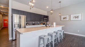 A modern kitchen with a central island, stainless steel appliances, and bar stools. - Des Moines Alluring 2BD 2BA Downtown Apartment (Des Moines)
