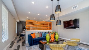 A modern living room with a blue sofa, yellow chairs, and a coffee table. - Des Moines Alluring 2BD 2BA Downtown Apartment (Des Moines)