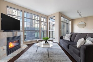 Una sala de estar moderna con chimenea, ventanas amplias, un sofá y una mesa de centro.