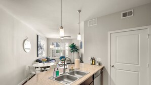 A modern kitchen with a granite countertop, stainless steel sink, and a ceiling fan. - Dallas Beautiful 1BD 1BA Downtown Apartment (Dallas)