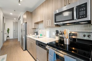 Eine moderne Küche mit Edelstahlgeräten, Holzschränken und einer gefliesten Spritzschutzwand.