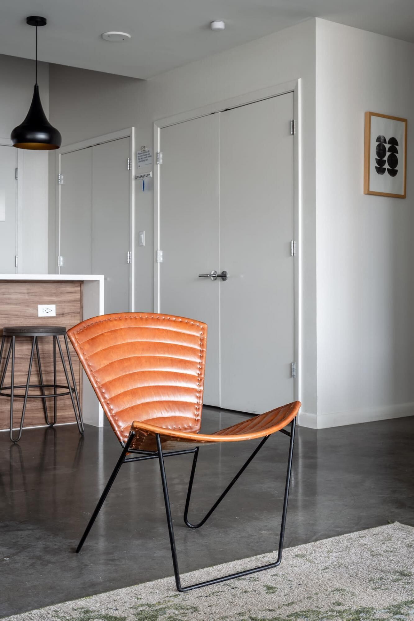 A modern interior with a leather chair, a wooden table, and a pendant light.