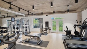 A spacious gym with various exercise equipment, large windows, and a clean, modern design.