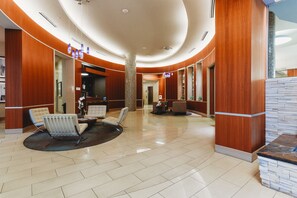 A spacious lobby with a curved ceiling, a reception desk, seating area, and a stone accent wall. - Austin Awesome Studio Apartment (Austin)