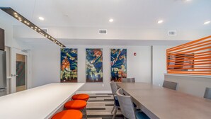 A modern conference room with a long table, orange bar stools, and abstract art on the walls. - Des Moines Heavenly 1BD 1BA Downtown Apartment (Des Moines)