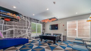 A room with a pool table, blue chairs, a TV, and a geometric patterned floor. - Des Moines Heavenly 1BD 1BA Downtown Apartment (Des Moines)
