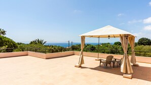 Eine Dachterrasse mit überdachter Sitzgruppe, einem Tisch und Stühlen.