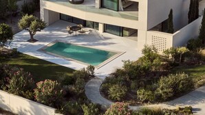 Ett modernt hus i två våningar med en takterrass, en swimmingpool och en vackert anlagd trädgård.