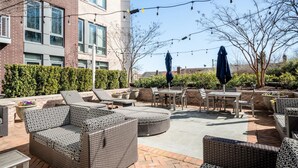 An outdoor patio with wicker furniture, string lights, and a view of a brick building. - Alexandria Alluring 2BD 2BA Apartment (Alexandria)