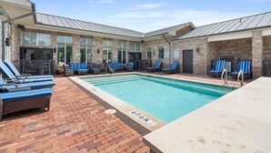 Un espace aménagé au bord de la piscine, avec des chaises longues et une terrasse en briques.