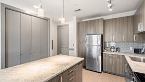A modern kitchen with a stainless steel refrigerator, wooden cabinets, and a granite countertop. - Arlington Stylish 2BD 2BA Apartment (Arlington)