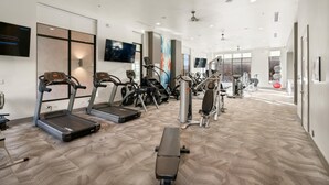 A modern gym with treadmills, elliptical machines, and weight equipment.