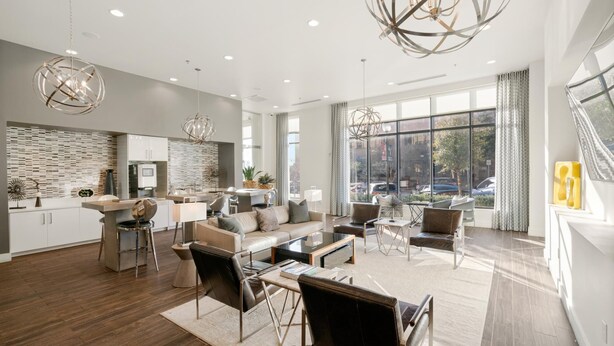 A spacious living area with a modern kitchen, large windows, and contemporary furniture.