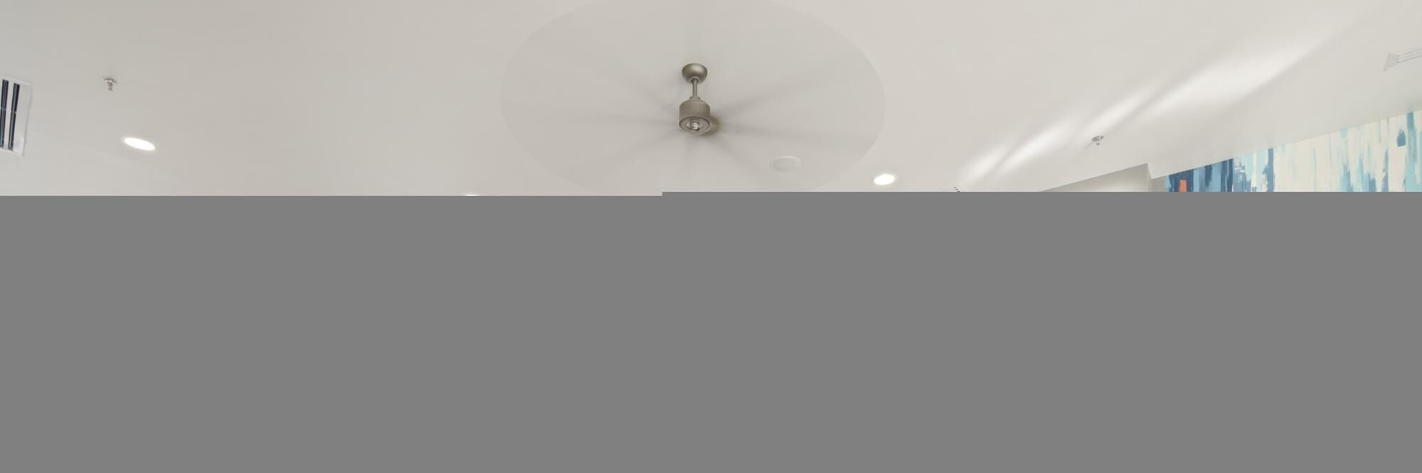 A ceiling fan in a room with a plain white ceiling and recessed lighting.