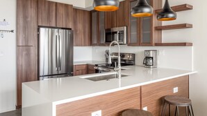 A modern kitchen with a stainless steel refrigerator, a microwave, and a coffee maker on the counter.