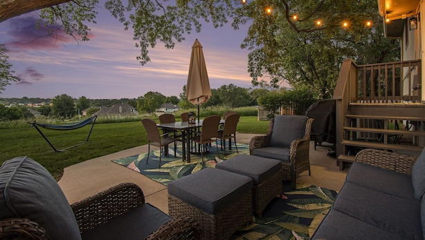 Une terrasse extérieure avec des meubles en osier, une table et des chaises.