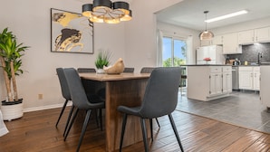 Une cuisine moderne avec des meubles blancs, une table à manger en bois et des chaises noires.