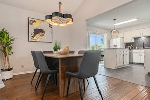 Een moderne keuken met witte kastjes, een houten eettafel en zwarte stoelen.