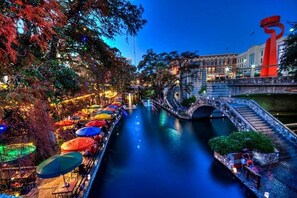 A riverside walkway with outdoor seating and a bridge. - 3 BR 1 BA Remodeled Home Near Downtown (San Antonio)