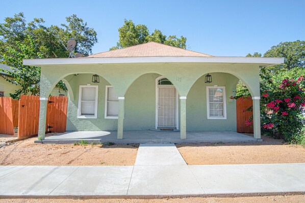 A single-story house with a covered porch, a front door, and two windows with shutters. - 3 BR 1 BA Remodeled Home Near Downtown (San Antonio)