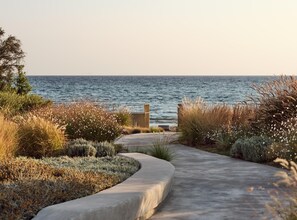 A coastal pathway leading to a beach with a metal gate, surrounded by native plants and grasses. - Butterflies Villas Spa-villa Plumeria (Zakynthos)