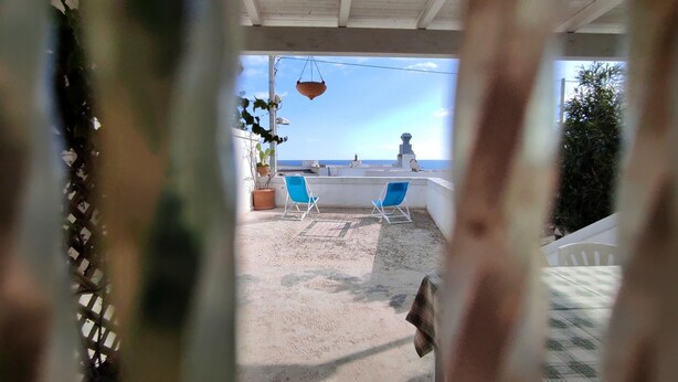 A terrace with two blue chairs, a hanging pot, and a view of the sea. - Casa Marieli - A 50 m dal Mare con Spazio Esterno (Gagliano del Capo)