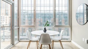 Een eetgedeelte met een ronde tafel, vier witte stoelen en een potplant.