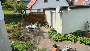Ein Wohngarten mit Terrasse, einer Holzterrasse und einem weißen Haus mit rotem Dach.
