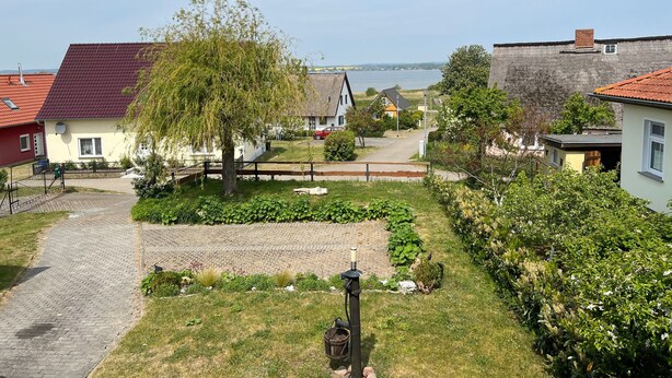 Ein Wohngebiet mit Häusern, einem Kopfsteinpflasterweg und Blick auf ein Gewässer.