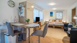 Een moderne kamer met een eettafel, stoelen, een televisie, een bed en een bank.