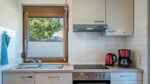 Een keuken met een raam, een spoelbak, een fornuis en een koffiezetapparaat.