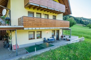Un bâtiment à deux étages doté d’un balcon, d’un espace extérieur aménagé pour s’asseoir et d’une table de ping-pong.