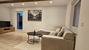Un salon moderne avec un canapé, une table basse, un téléviseur et un tableau accroché au mur.