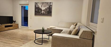 A modern living room with a sofa, a coffee table, a TV, and a painting on the wall.