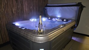 Un jacuzzi avec une bouteille de champagne et des verres, un panneau de commande et un mur en bois en arrière-plan.