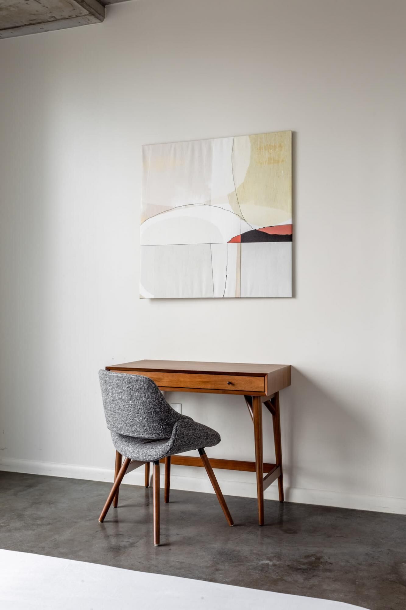 A modern room with a wooden desk and a grey chair.