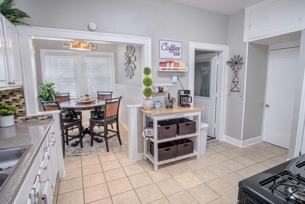 A kitchen with a dining area, white cabinets, a coffee station, and a gas stove. - Stunning 3 BR Home Near DT Alamodome - Riverwalk (San Antonio)
