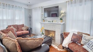 Ein Wohnzimmer mit Kamin, zwei Sofas und einem Fernseher.