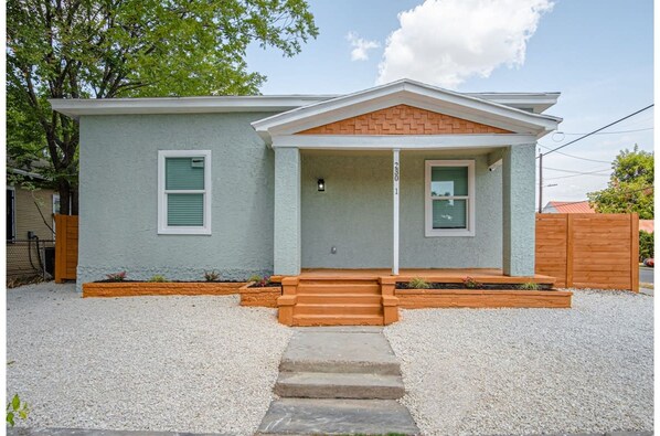 A single-story house with a front porch, a small entryway, and a gravel driveway.