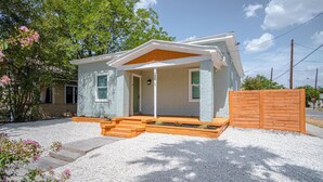 A modern house with a porch, a wooden fence, and a gravel driveway.