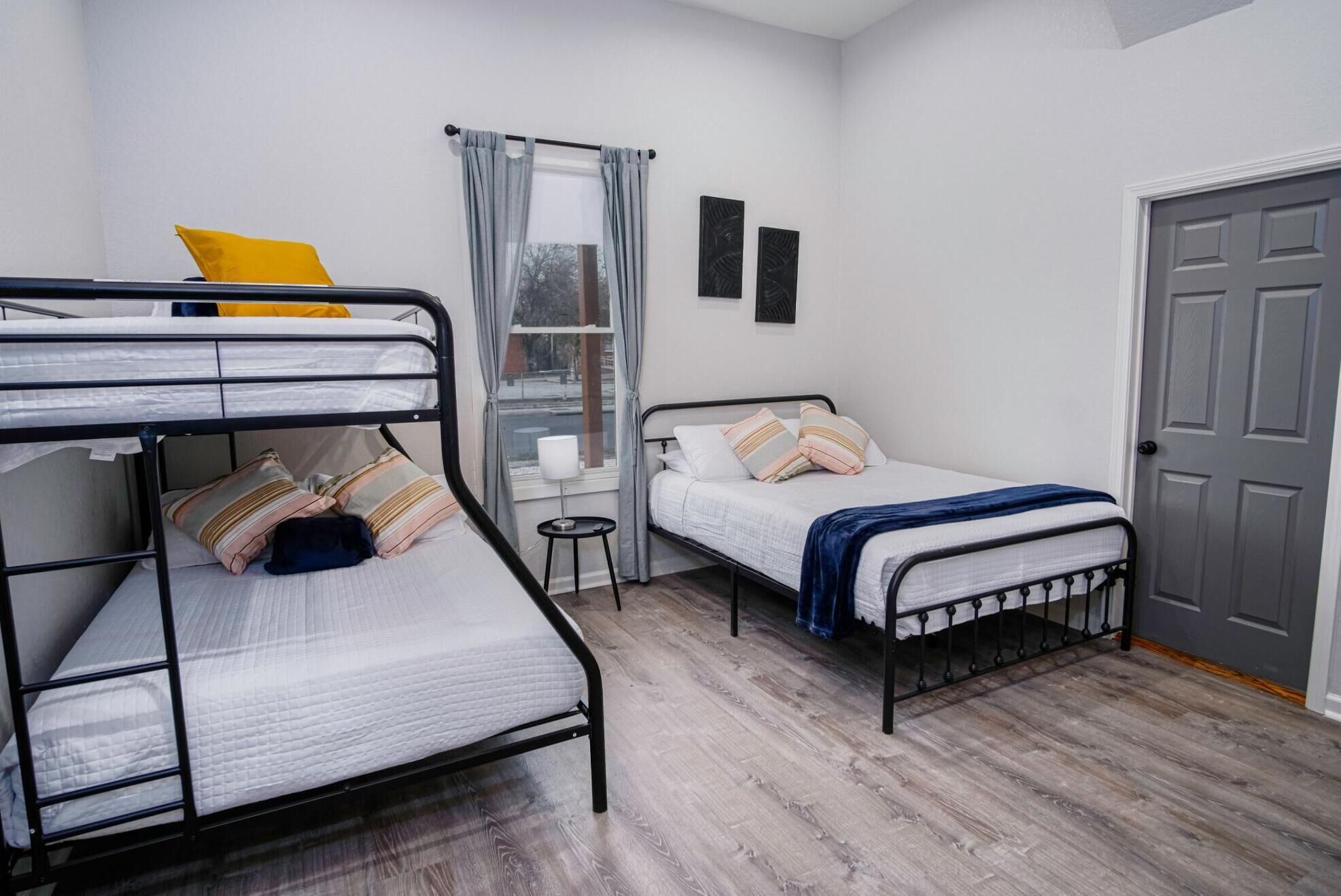 Een kamer met stapelbedden, een enkele bed, een klein tafeltje en een deur.