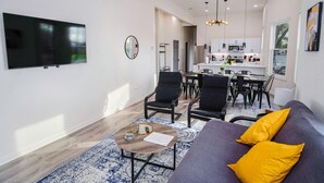 A modern living room with a sofa, coffee table, and dining area. - Magnificent 4BR Near Famous Riverwalk and Downtown (San Antonio)