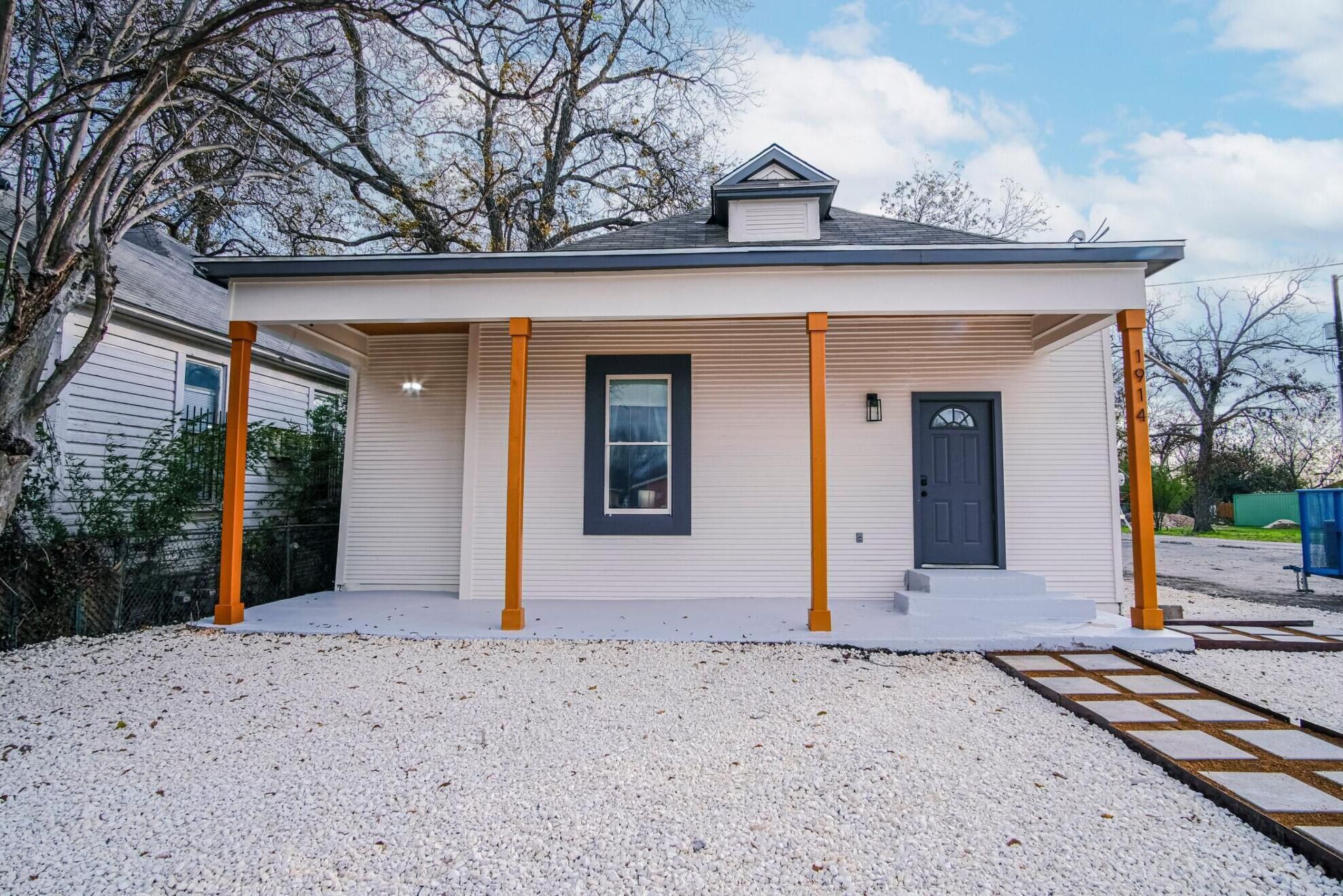 A single-story house with a covered porch, a front door, and a small window.