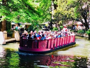 A narrow boat with passengers, surrounded by lush greenery and a calm water body. - Stunning Cozy Downtown Guesthouse (San Antonio)