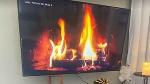 Un televisor de pantalla plana montado en la pared sobre un mueble negro con chimenea abajo.