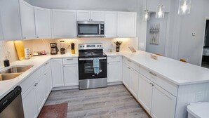A modern kitchen with white cabinets, stainless steel appliances, and pendant lighting. - Exceptional 5BR So Close to Riverwalk and Downtown (San Antonio)