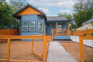 A small house with a porch, a fenced yard, and a clear sky. - Exceptional 5BR So Close to Riverwalk and Downtown (San Antonio)