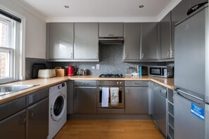 A modern kitchen with grey cabinets, a built-in oven, microwave, and dishwasher.